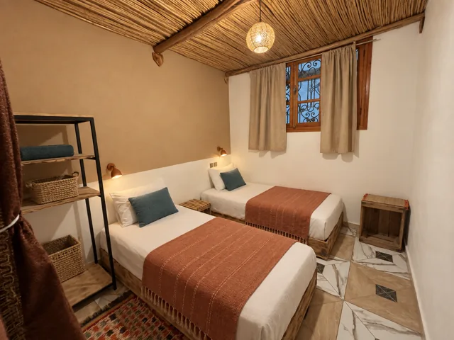 Twin beds with woven reed ceilings, clay throws and blue cushions