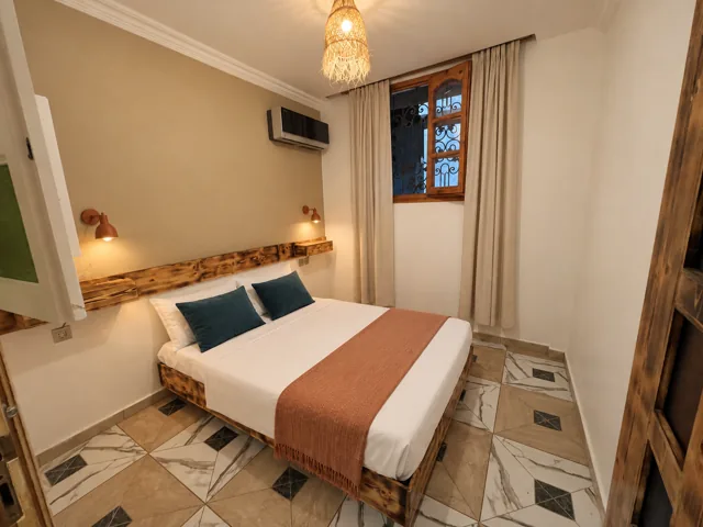 A timber double bed with woven details and warm clay bedding