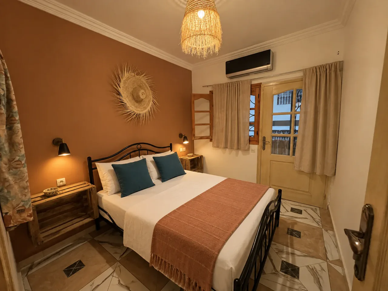 An iron double bed with clay textiles and warm bedside lighting