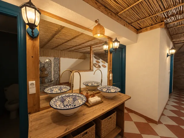 A shared wash area with basins, mirrors and warm tile finishes