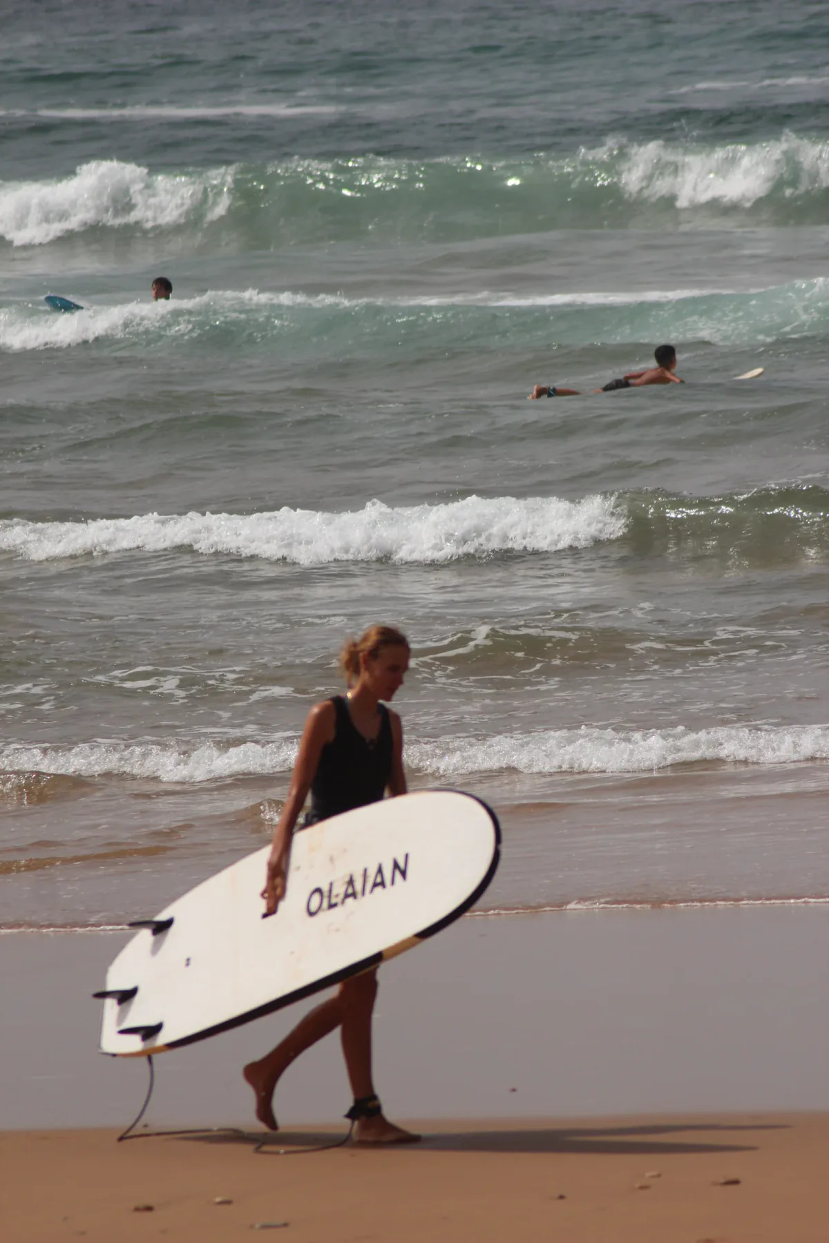 Une surfeuse revient de la mer avec sa planche
