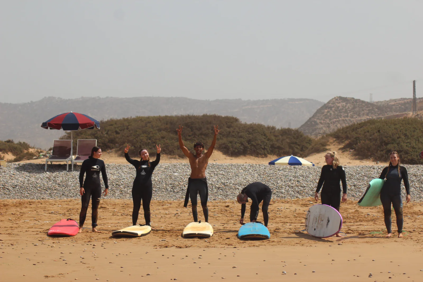 Surfers smiling together on the beach with their boards