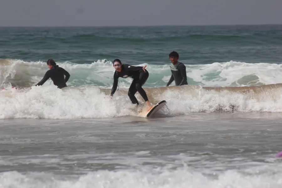 A learner finding her feet on a surfboard in the whitewater