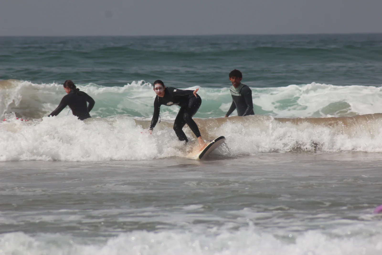 A learner finding her feet on a surfboard in the whitewater