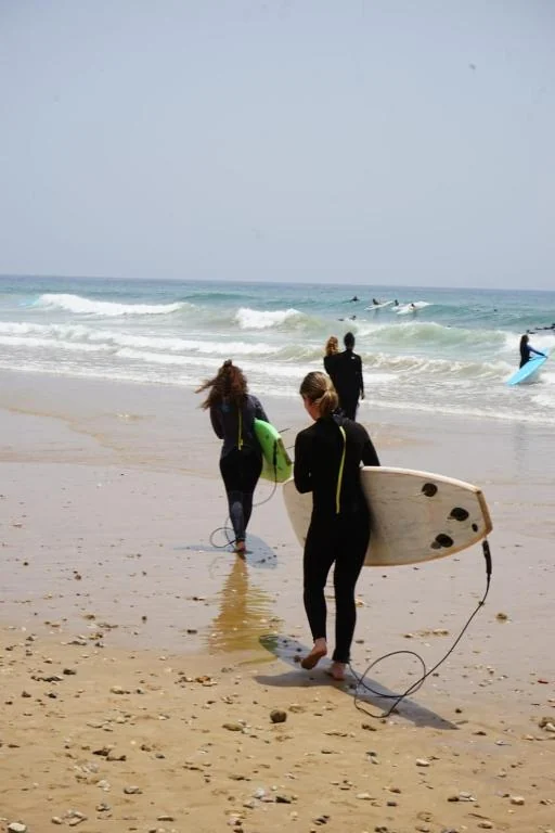 Des surfeurs portent leurs planches vers les vagues